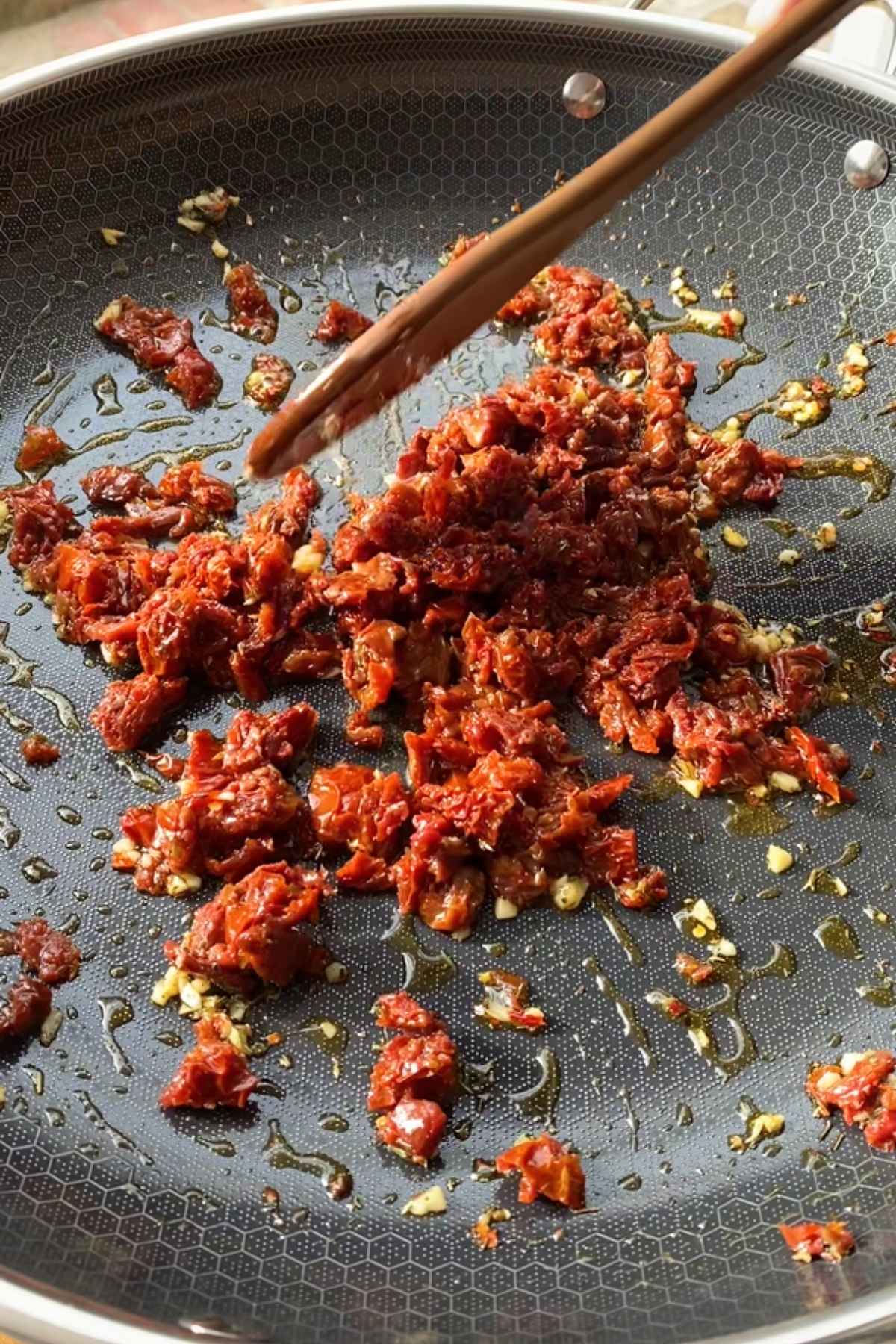 Chopped sun-dried tomatoes cooking in the skillet with garlic.
