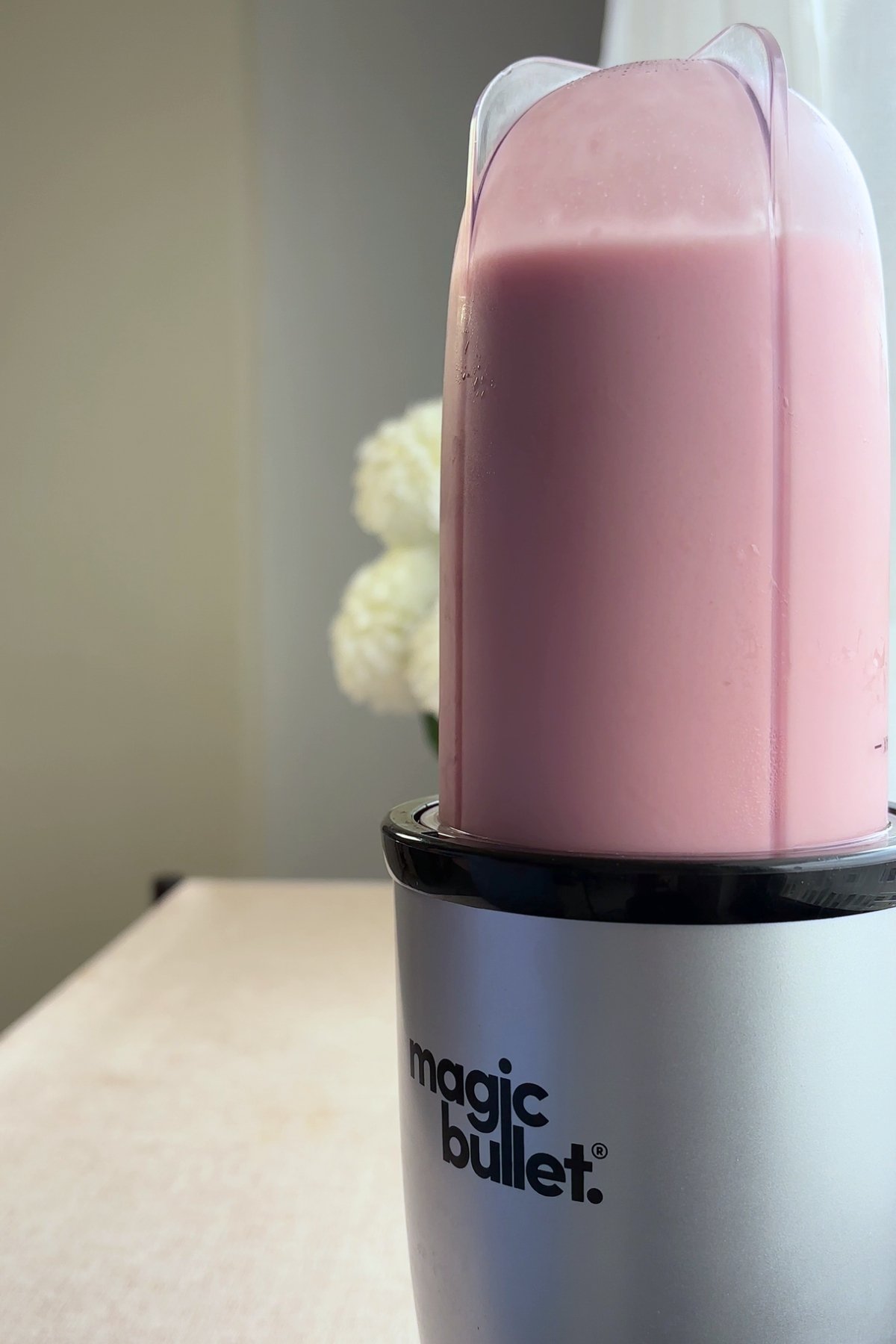 Blending pink sorbet mixture in a Magic Bullet blender.