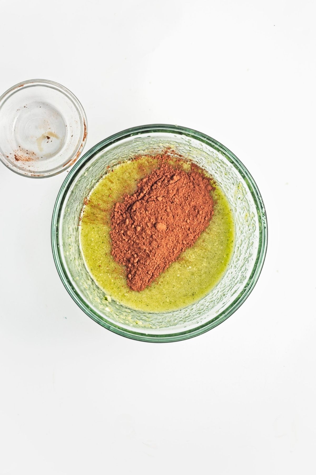 Cocoa powder added to the wet mixture in a glass bowl.