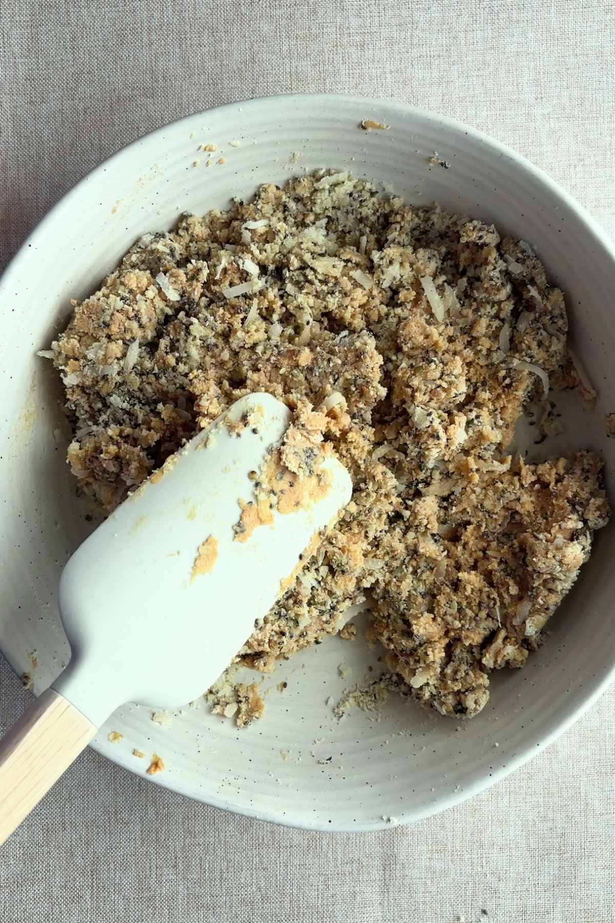 Partially mixed protein ball dough with a spatula in the bowl.