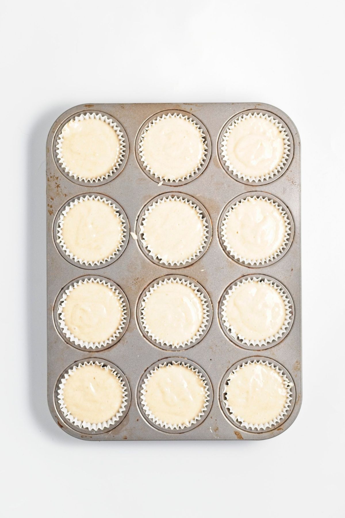 Cupcake batter portioned into a lined muffin pan before baking.