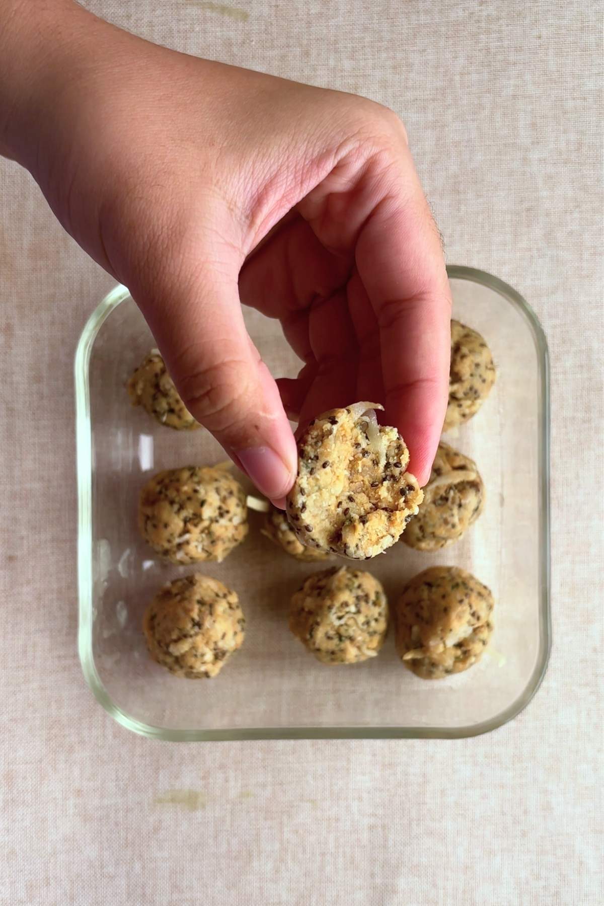 Hand holding a bitten protein ball over the container.