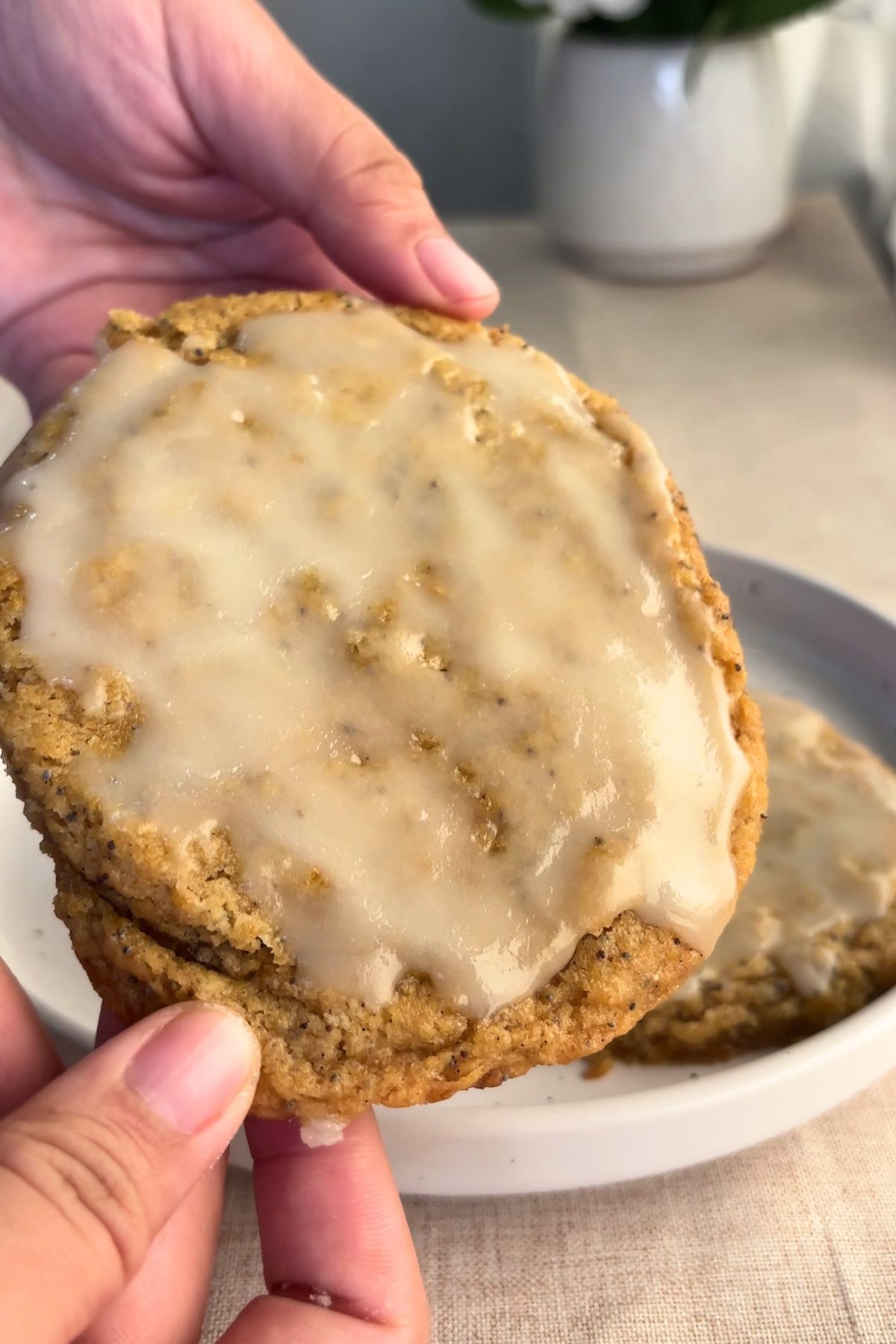 Hand holding a glazed cookie stacked over another.