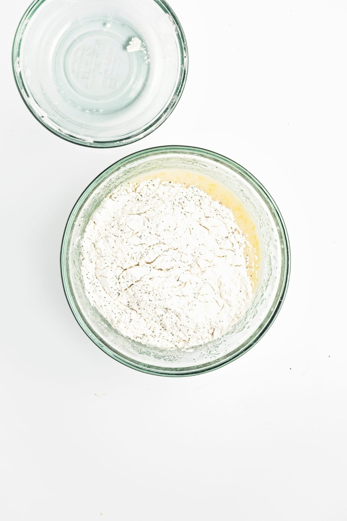 Bowl with dry flour mixture on top of wet batter, ready to mix.