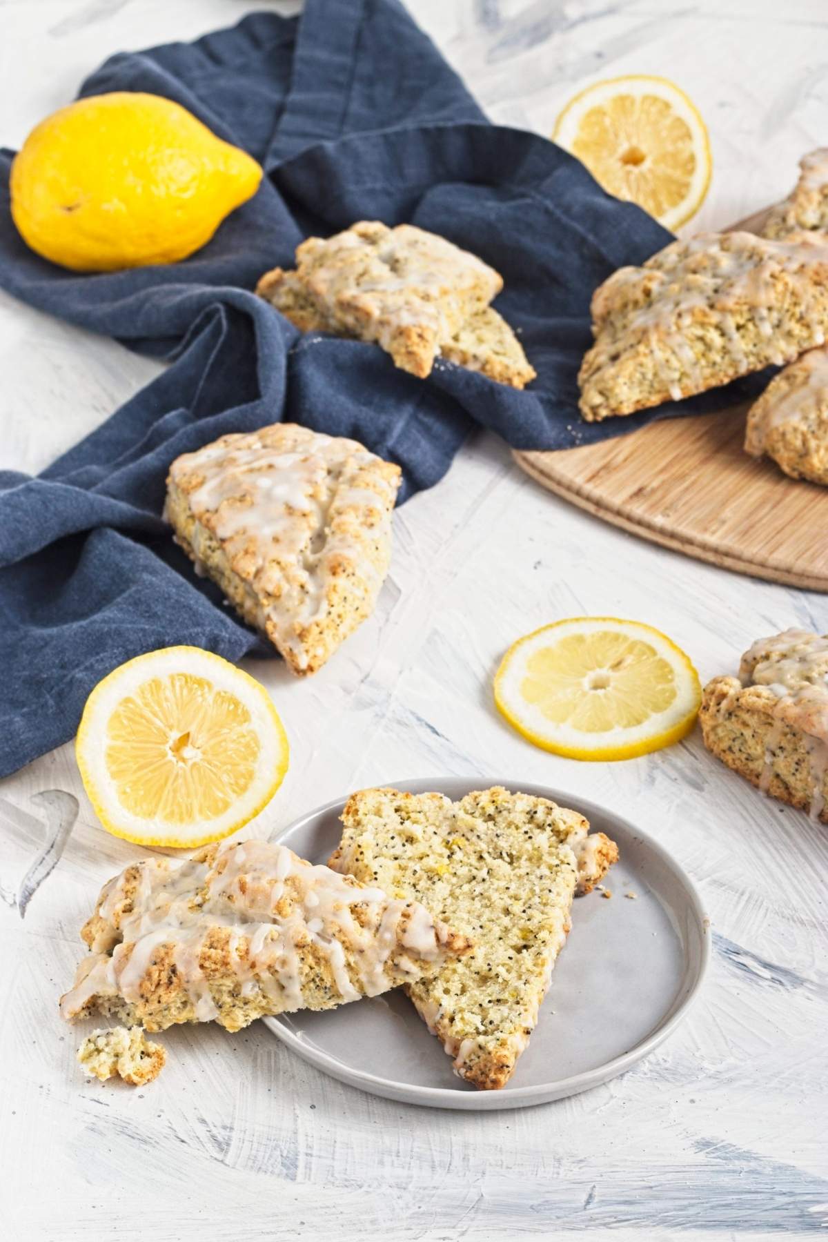 Plate with a sliced scone showing crumb texture, surrounded by more scones and lemon slices.