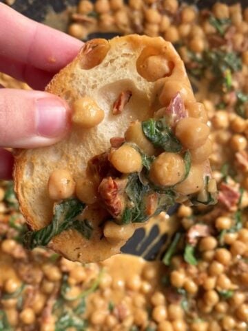 Slice of bread topped with creamy chickpeas and spinach.