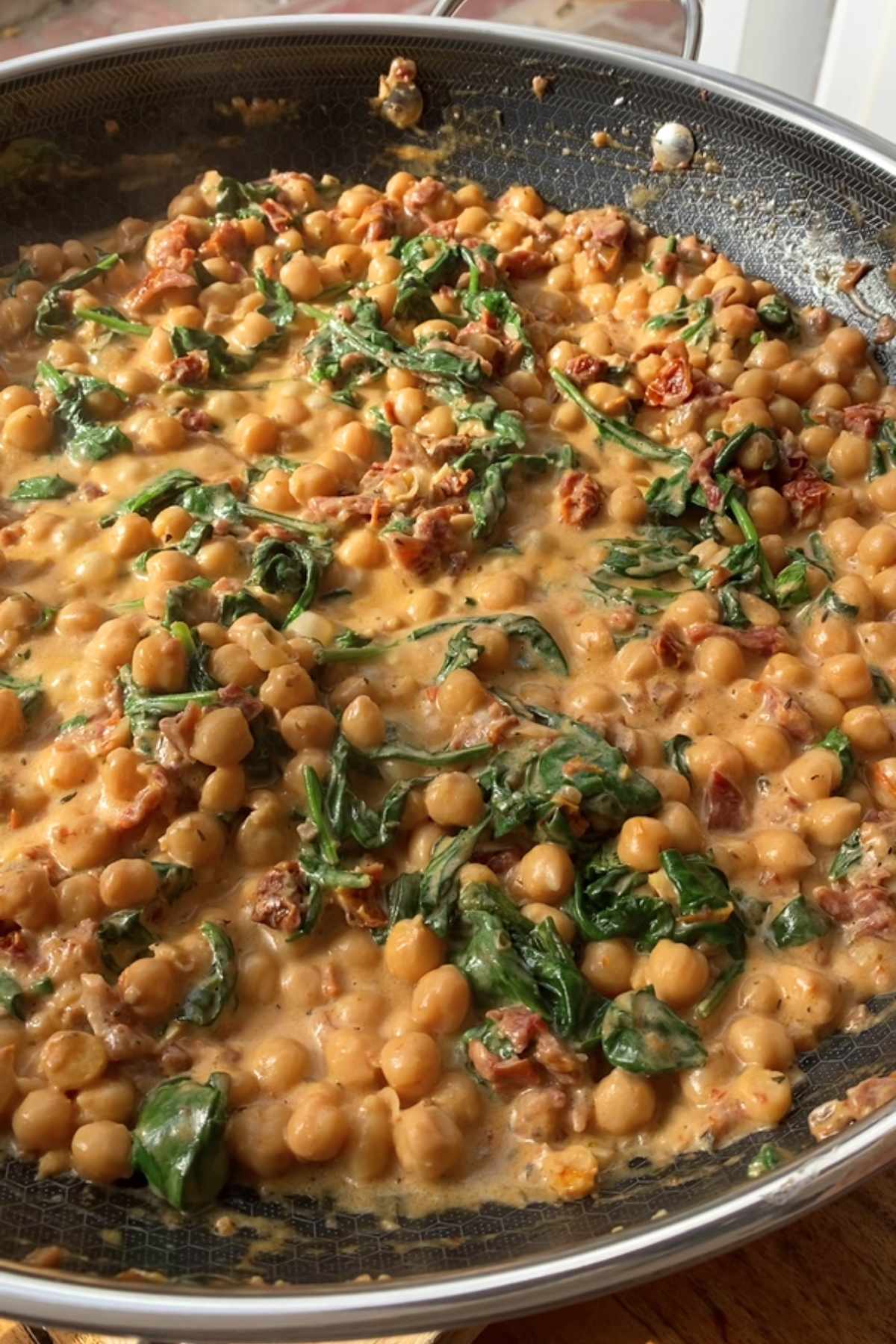Skillet filled with chickpeas, spinach, and creamy tomato sauce.