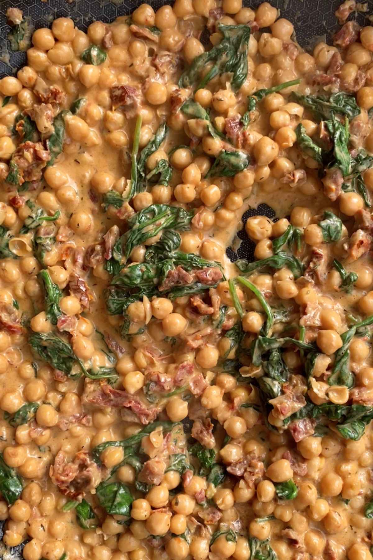 Overhead view of chickpeas and spinach in creamy sauce.