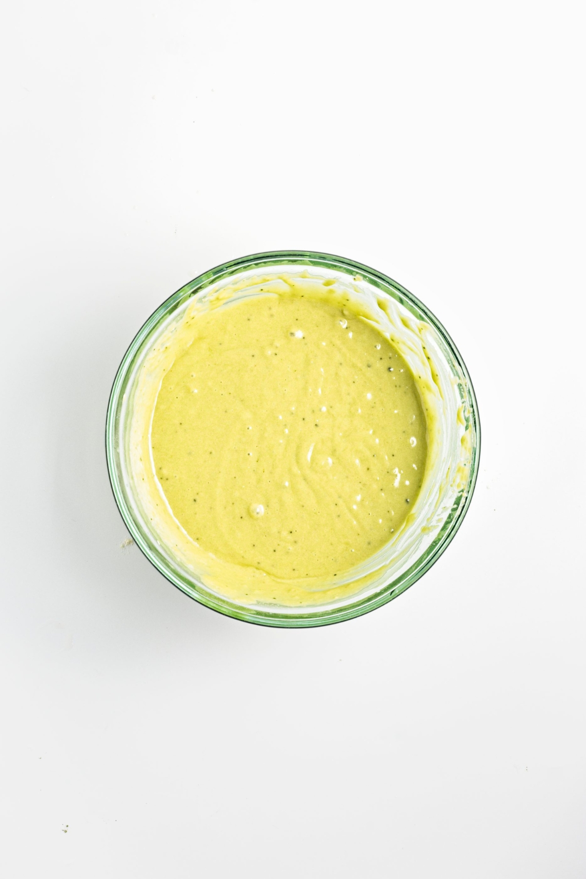 Green muffin batter in a glass mixing bowl.