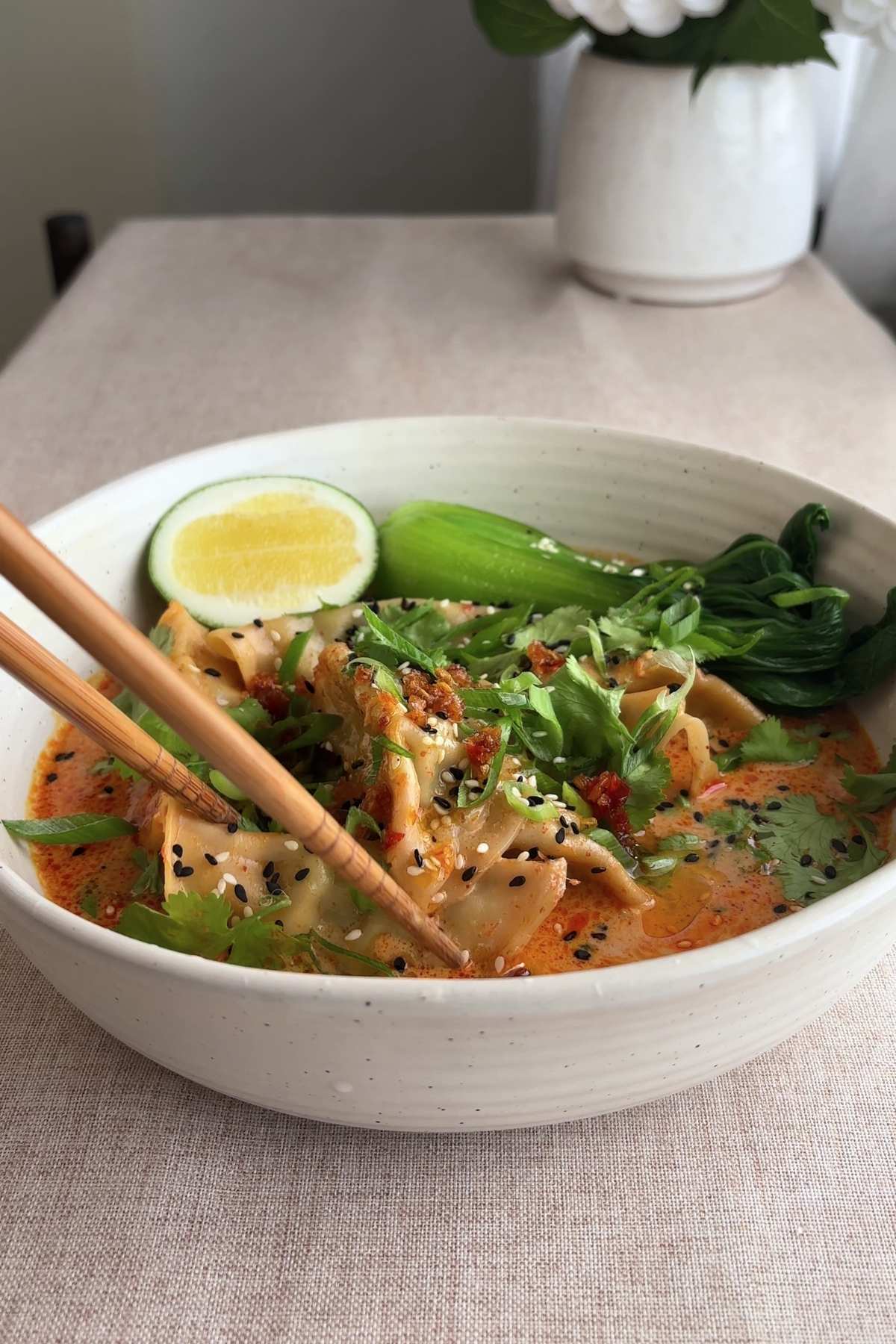 Bowl of dumpling soup with chopsticks resting on the side.