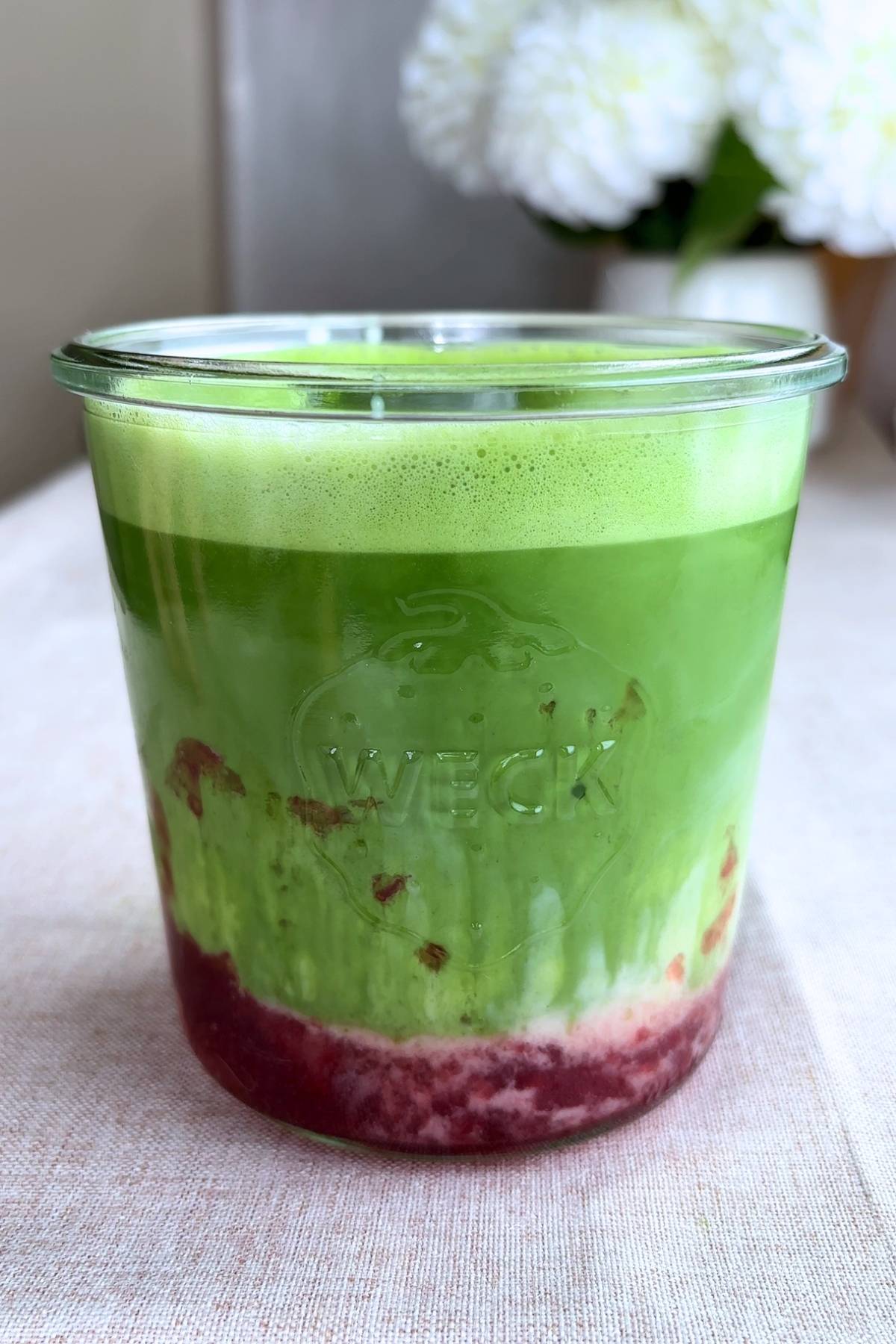 Iced strawberry matcha latte with blended green matcha and jam settled at the bottom.