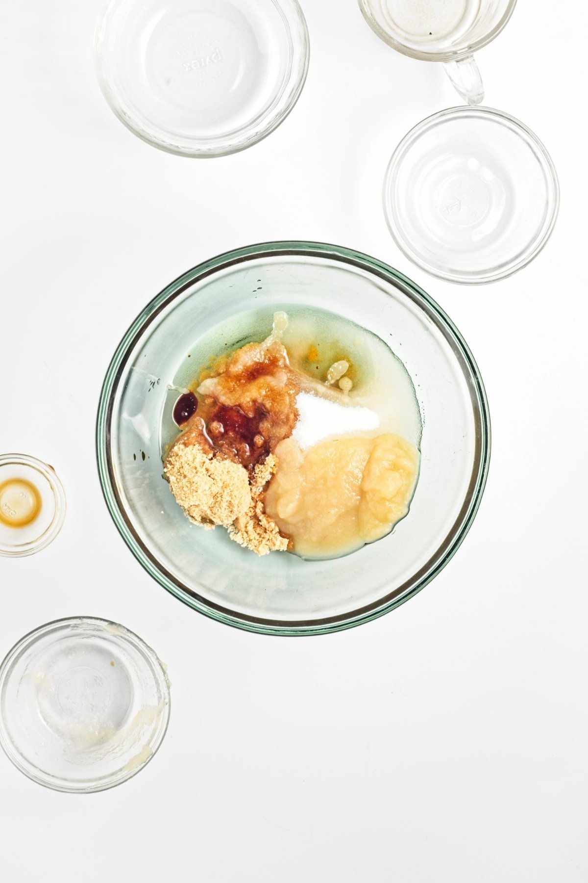 Bowl with applesauce, brown sugar, white sugar, vanilla, and other wet ingredients before mixing.