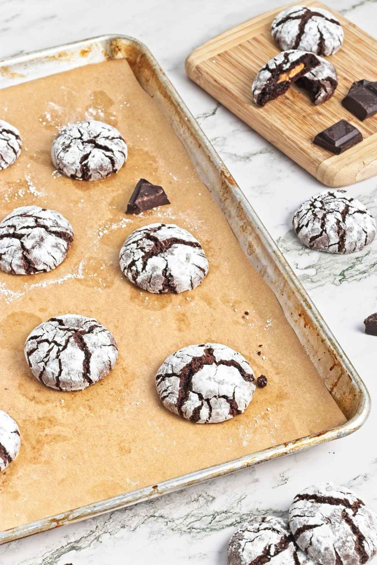 Baked crinkle cookies on a tray with a bitten cookie in the foreground.