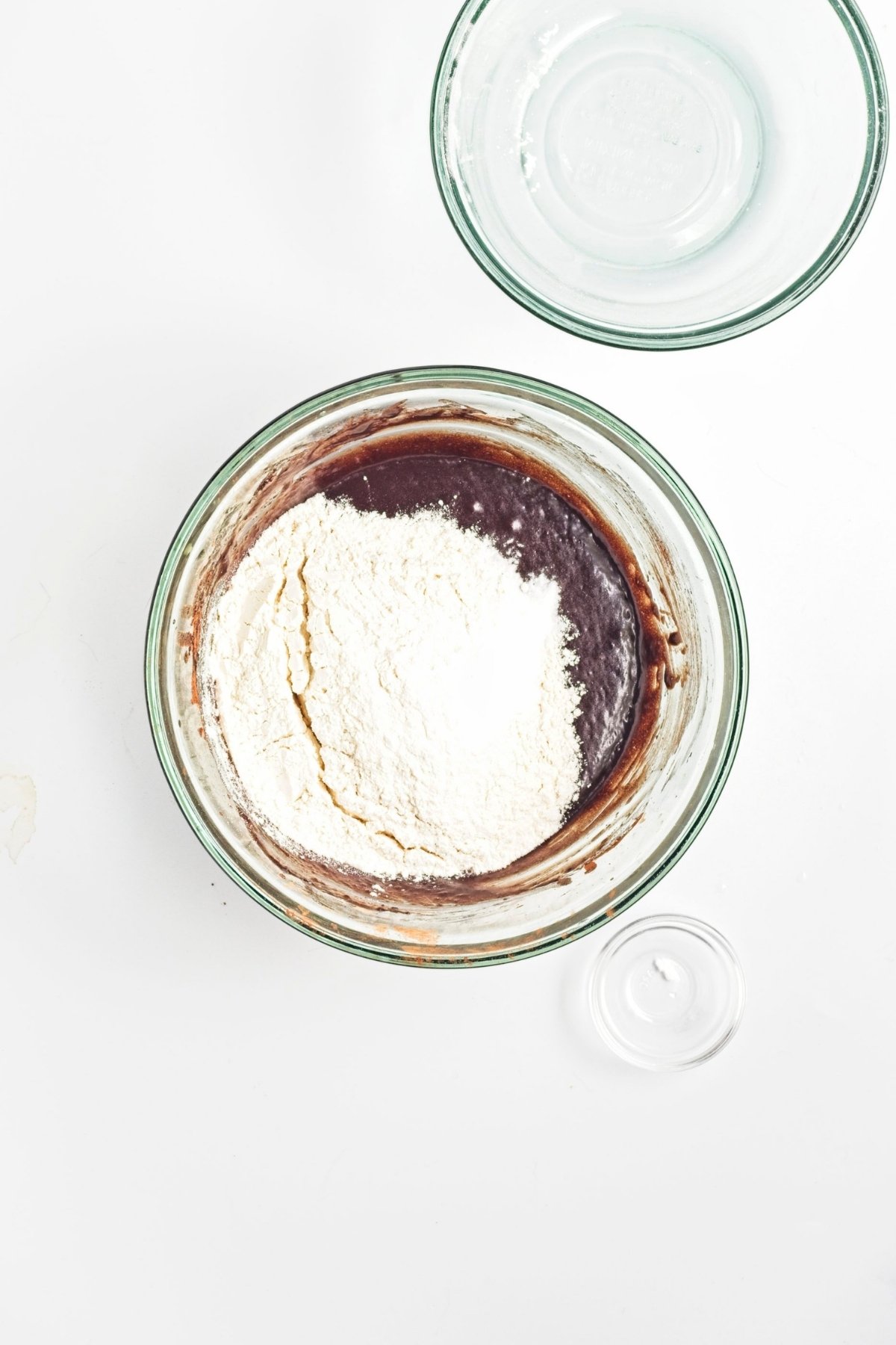 Mixing bowl with chocolate batter and flour on top, ready to be folded in.