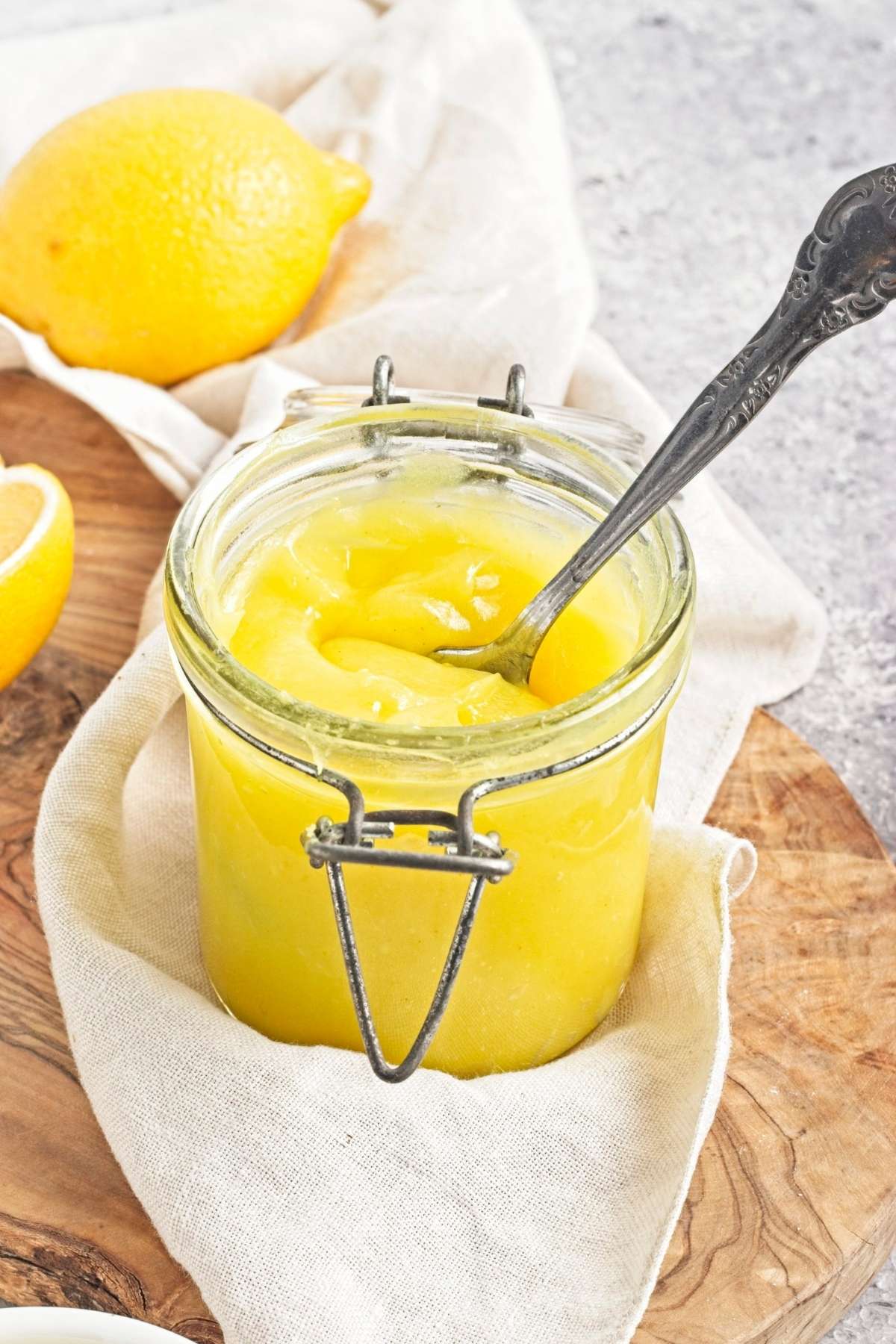 Close-up of an open jar filled with yellow curd and a spoon inside.