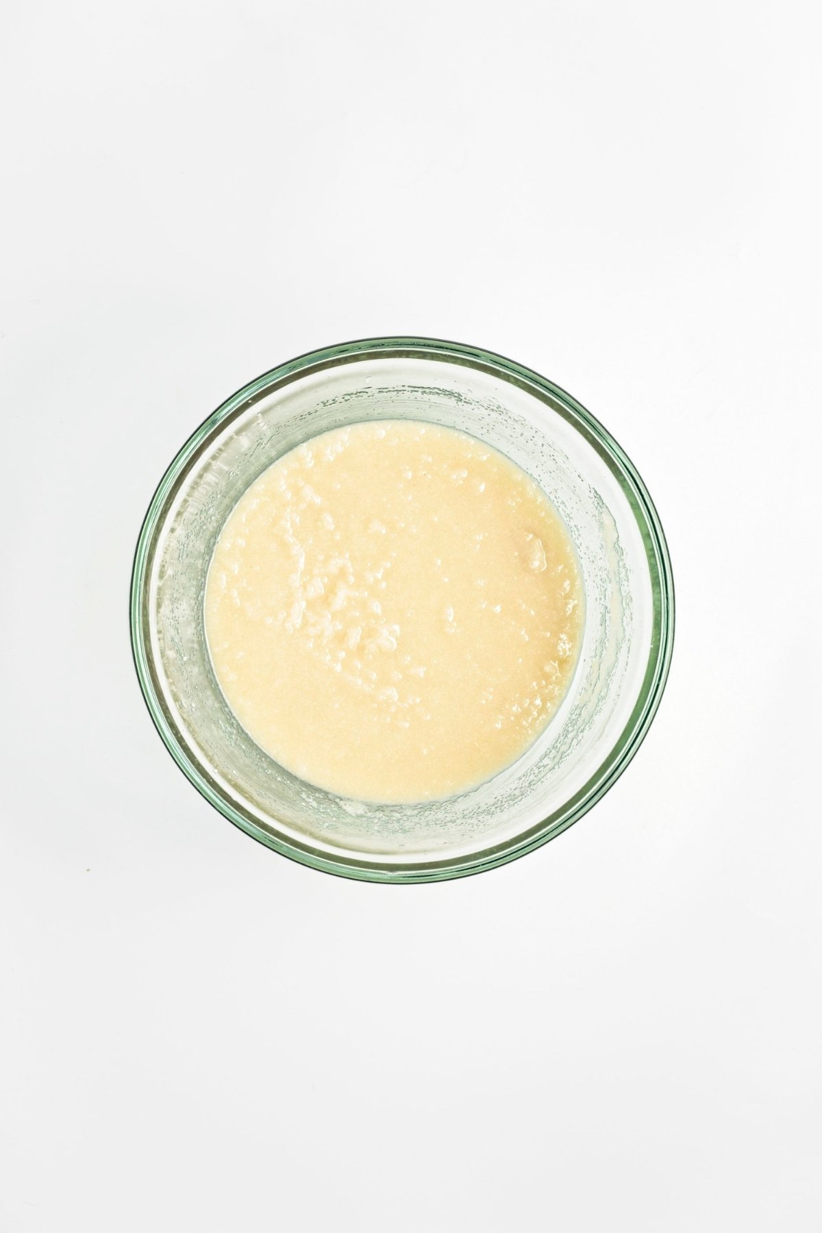 Mixing bowl with a blended mixture of oil, sugar, tahini, and oat milk.