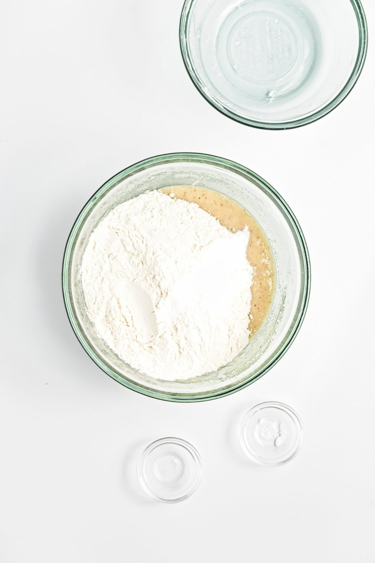 Mixing bowl with wet mixture topped with flour, salt, and baking soda.
