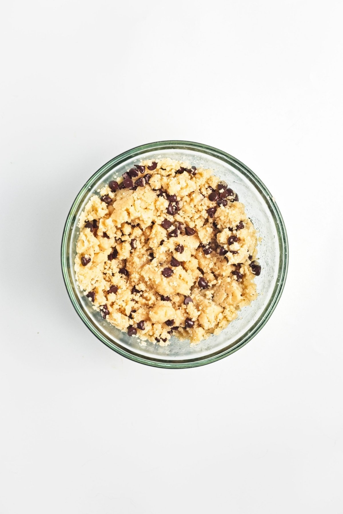Mixing bowl with crumbly cookie dough and dark chocolate chips folded in.