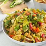 Large bowl of chopped lettuce, chickpeas, tomatoes, cucumber, and tortilla chips tossed together.