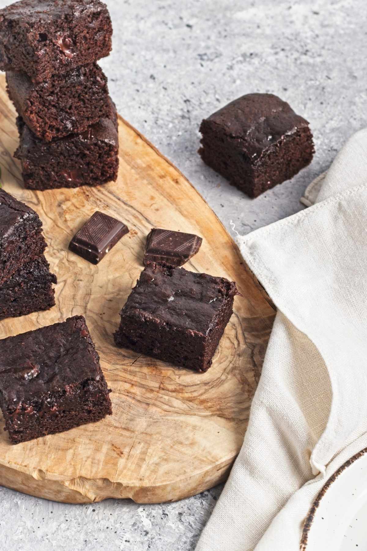 Cut brownies on a wooden board with chocolate pieces.