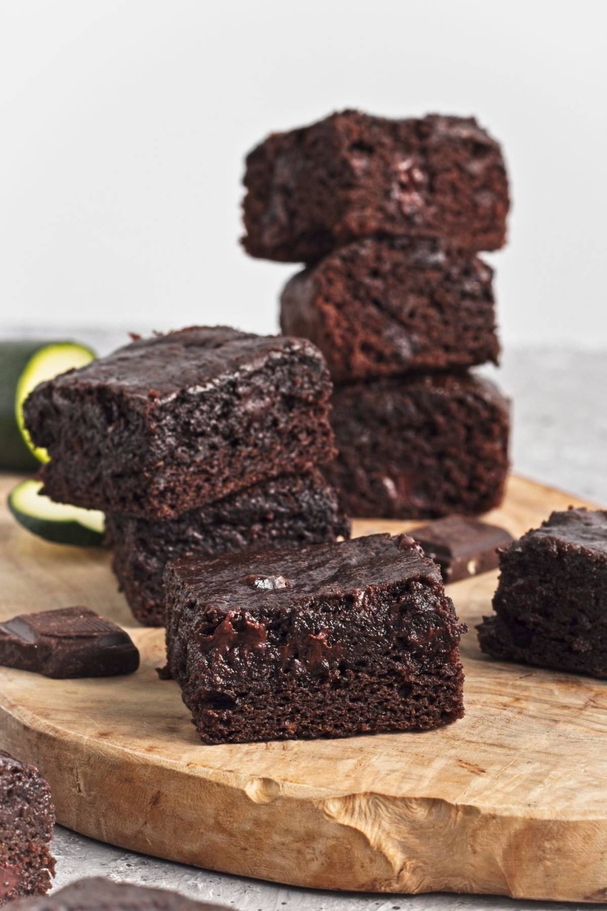 Stack of moist brownies with visible chocolate chunks on a wooden board.