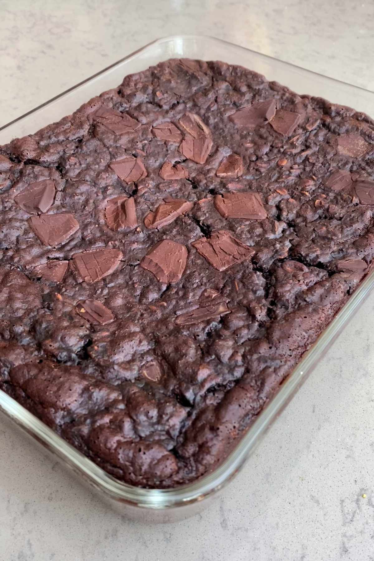 Close-up of baked chocolate oat brownies topped with chunks of dark chocolate.