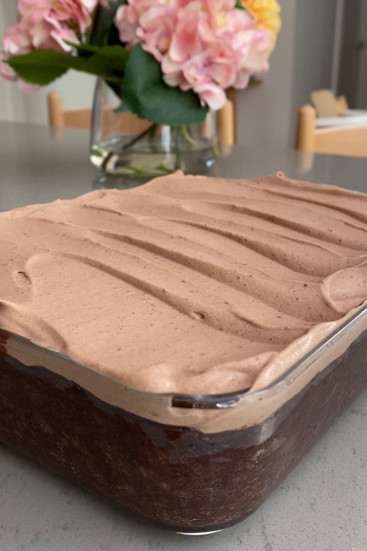 Glass dish filled with baked chocolate oats topped with smooth chocolate yogurt frosting.