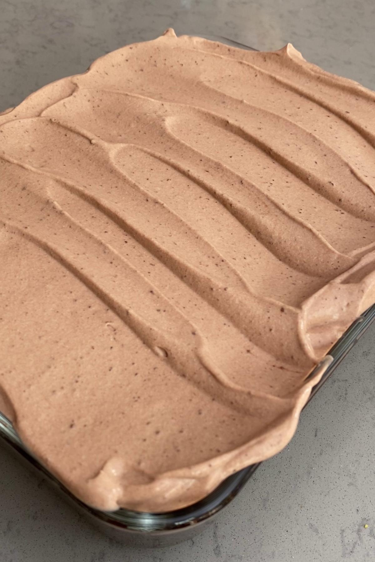 Thick layer of chocolate yogurt frosting spread evenly across baked chocolate oats.