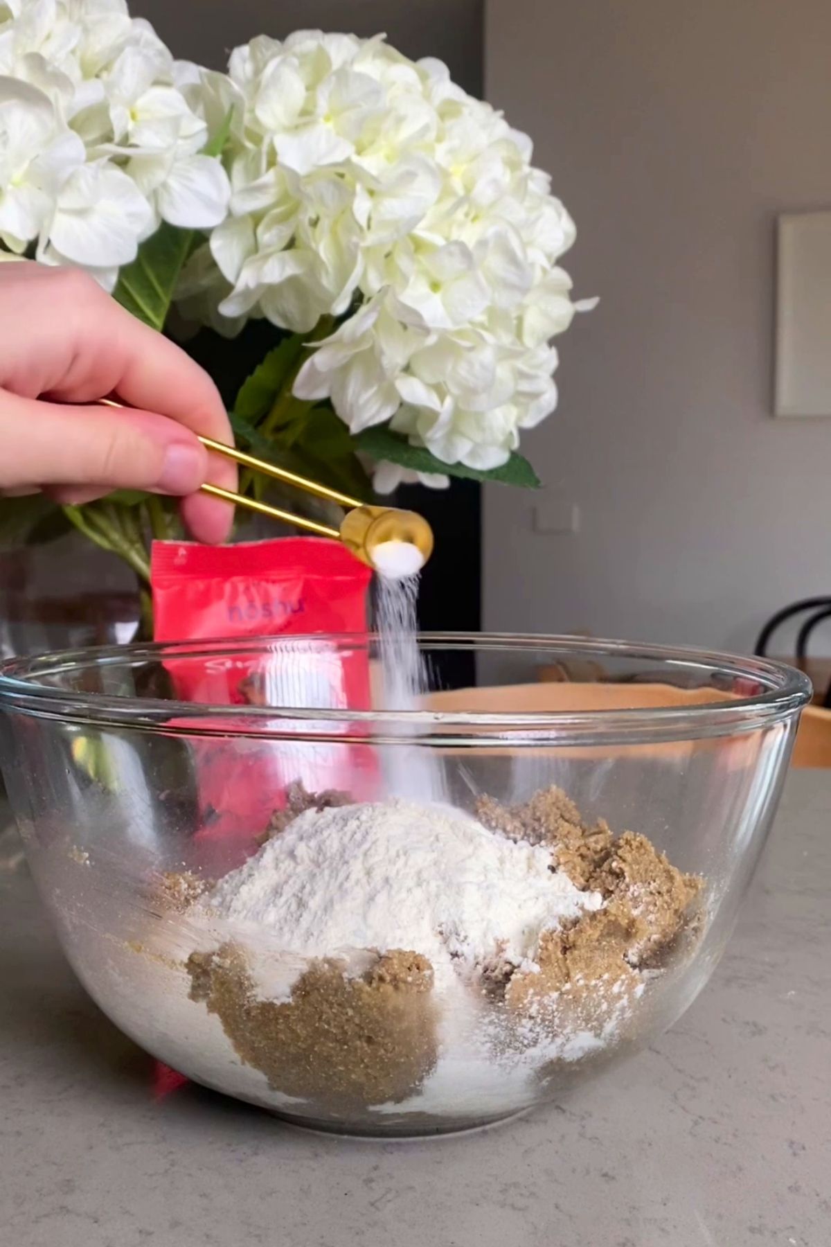 Flour and baking soda being added into the mixing bowl with brown sugar mixture.