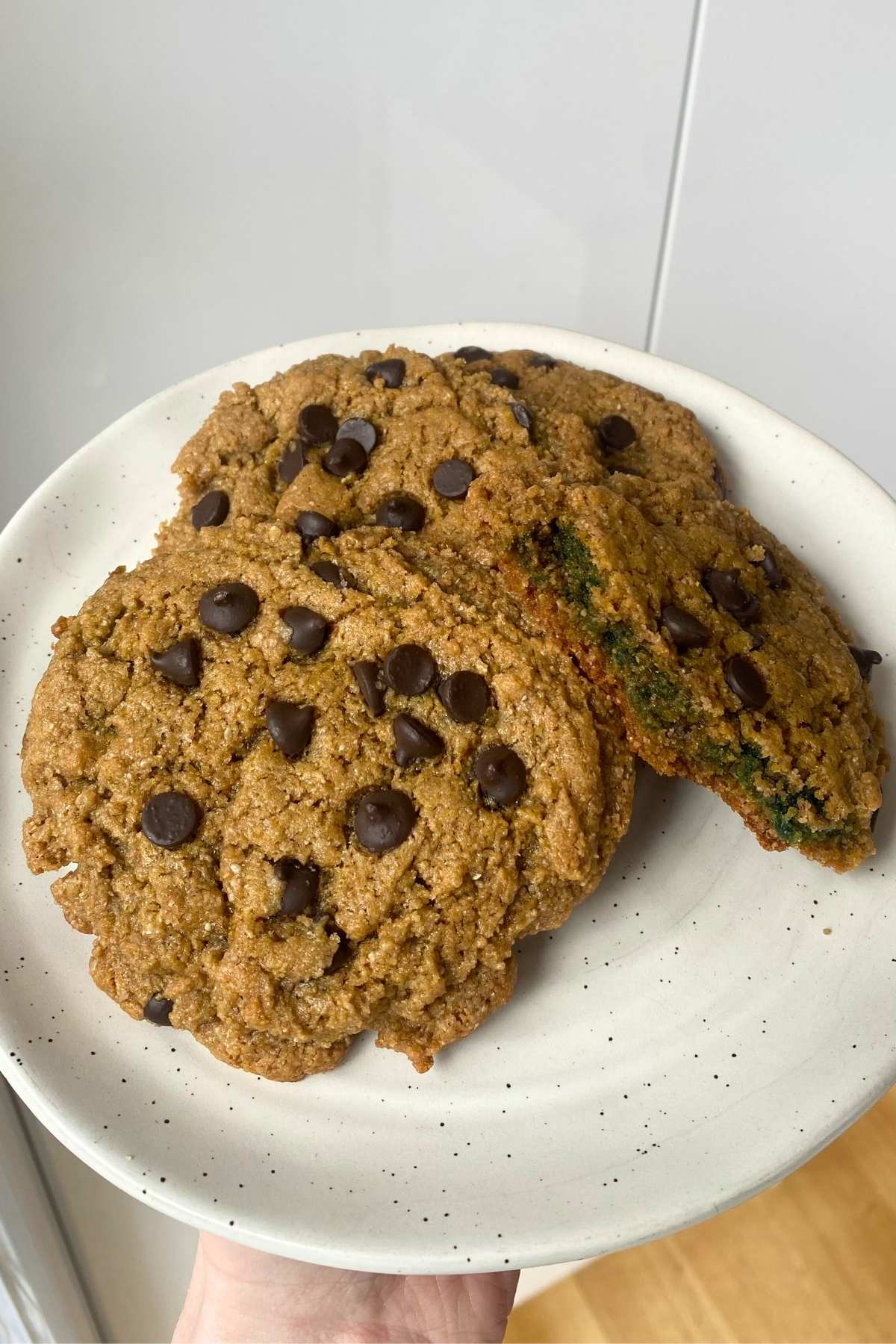 Baked cookies on a plate, one broken open to reveal green-tinted center.
