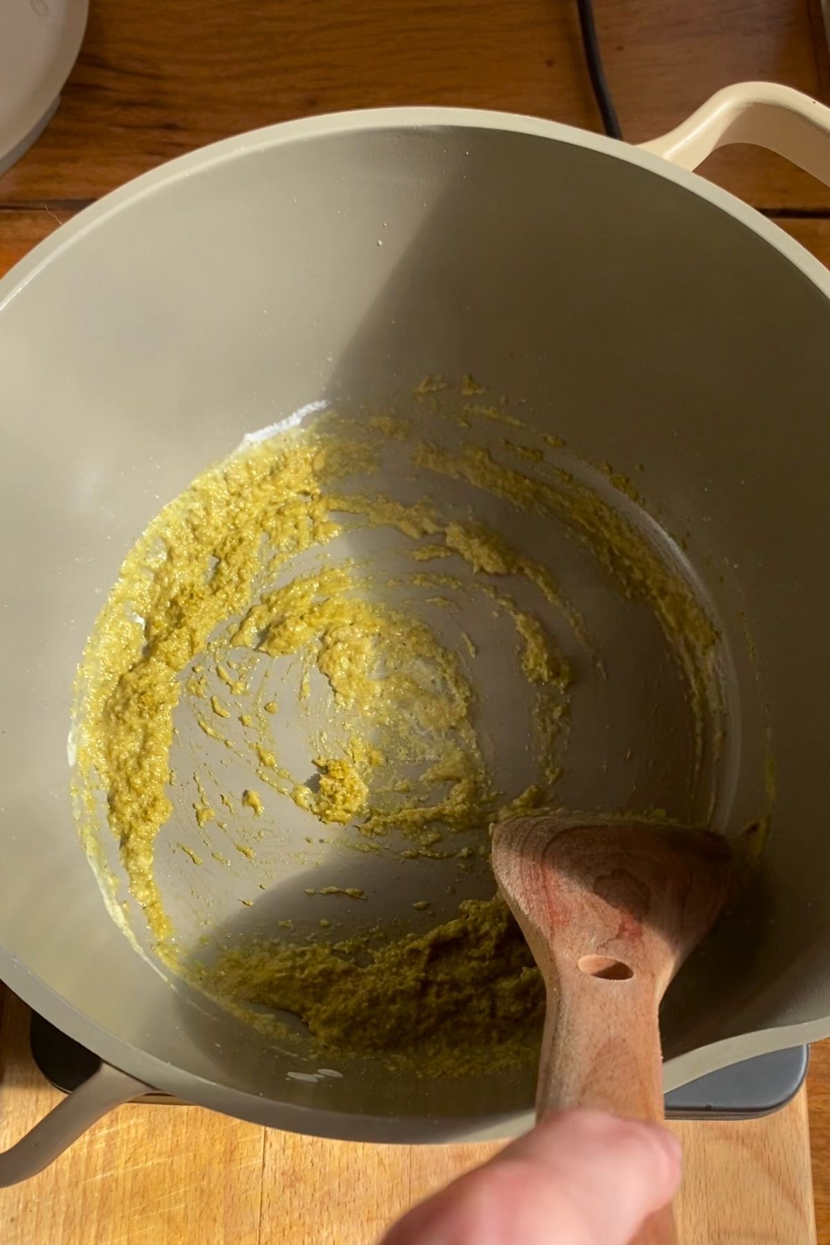 Curry paste sizzling in a pot with a wooden spoon.