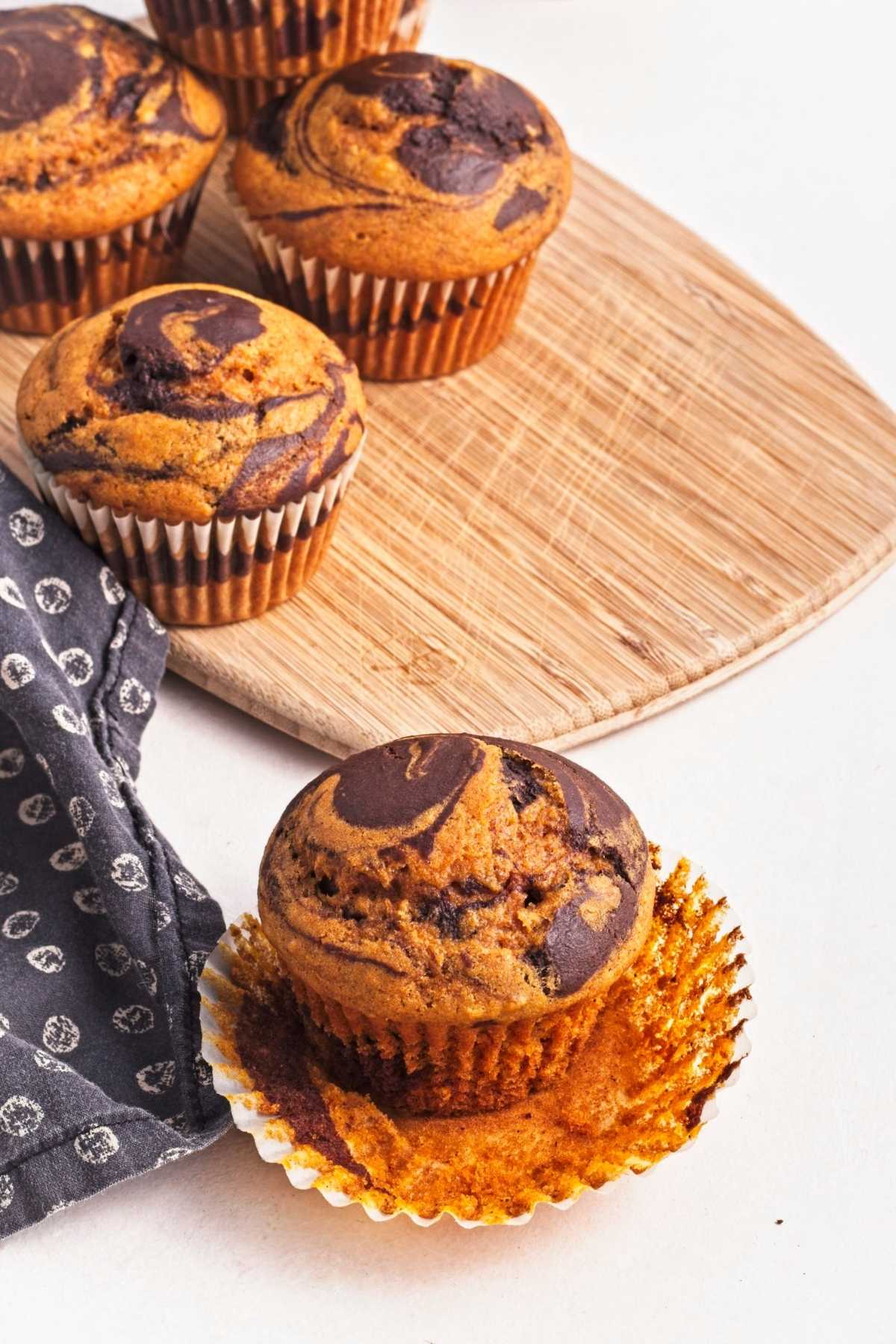 Pumpkin chocolate swirl muffins on a wooden board.