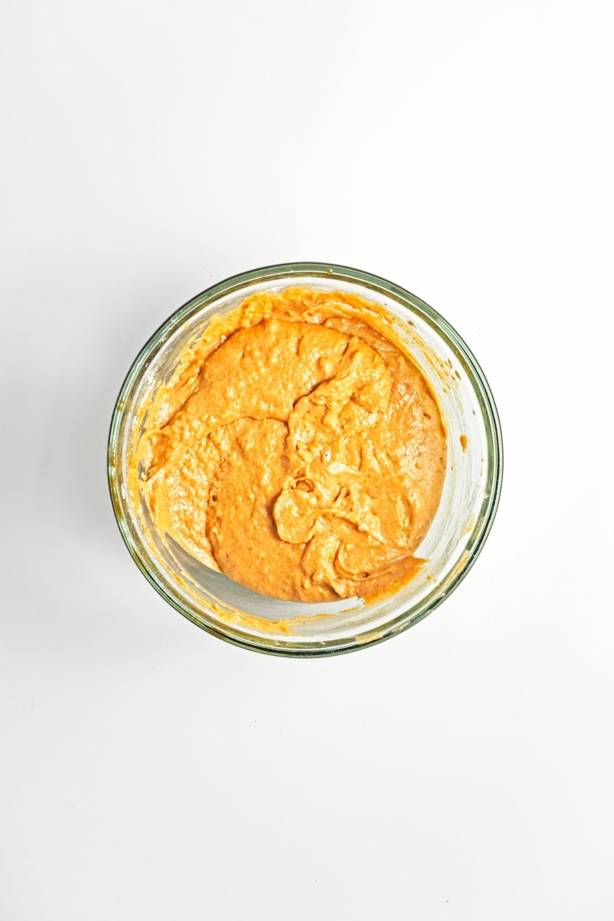 Pumpkin batter mixed until smooth in a glass bowl.