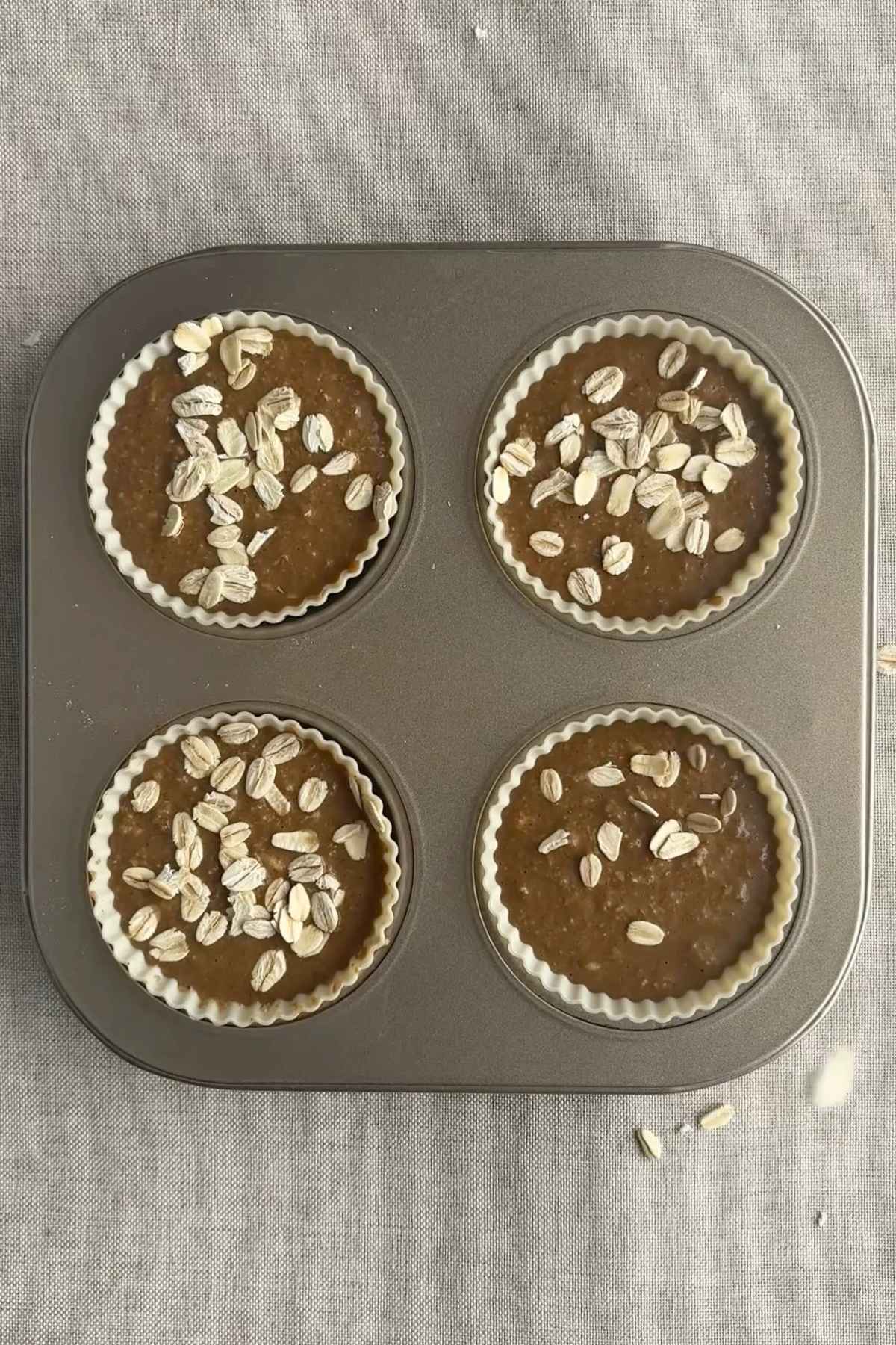 Muffin batter poured into silicone liners topped with oats.