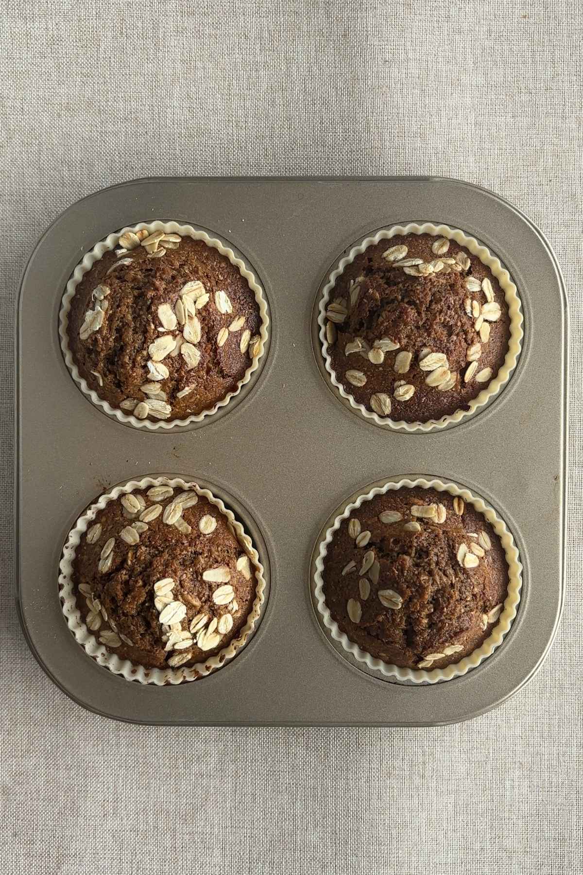 Baked muffins in a pan, golden brown with oat topping.