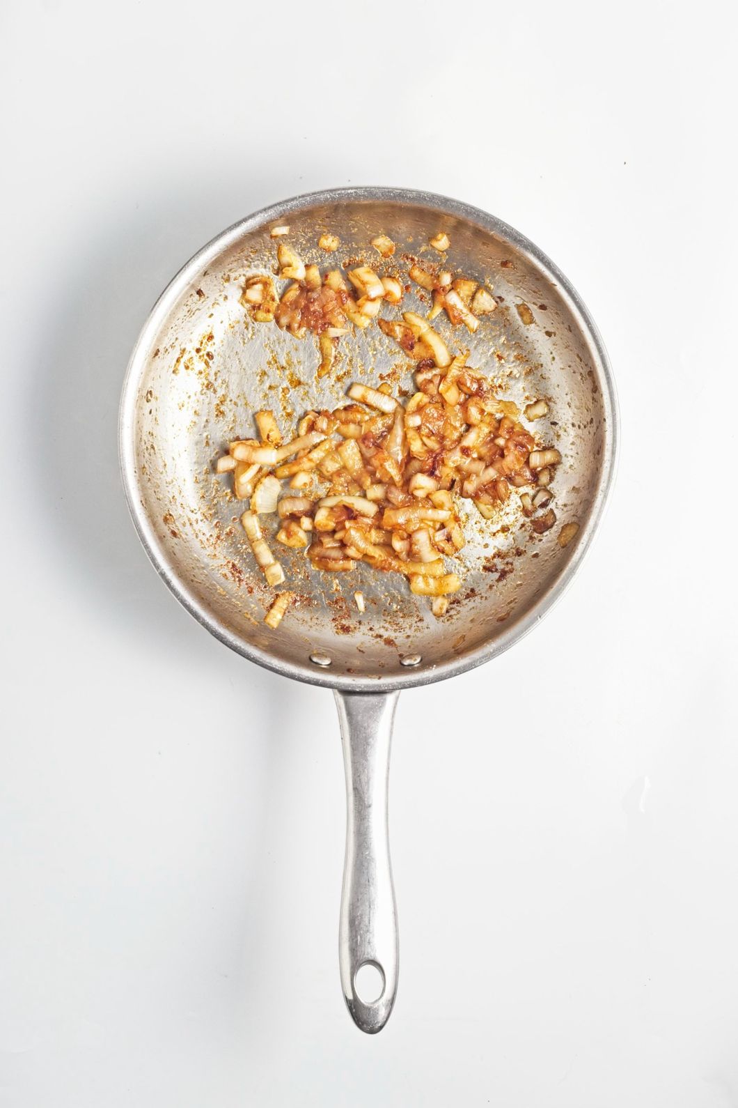Golden caramelized onions cooking in a stainless steel frying pan.