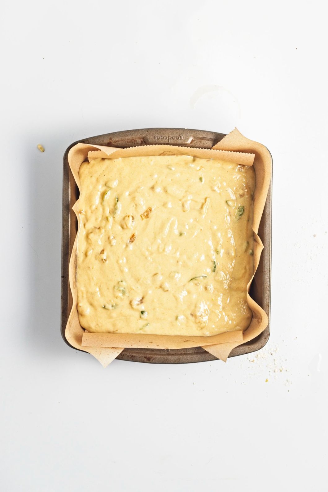 Cornbread batter poured into a parchment-lined square baking pan.