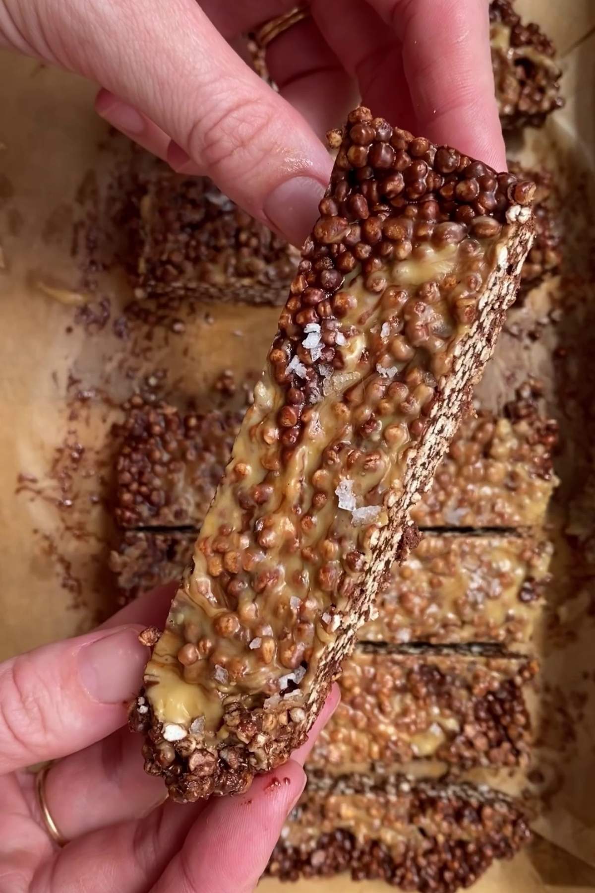 Close-up of a chocolate quinoa bar showing crunchy layers and peanut butter topping.
