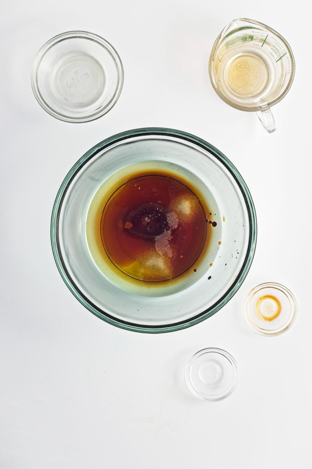 Maple syrup, oil, vanilla, and salt combined in a glass mixing bowl on a white surface.