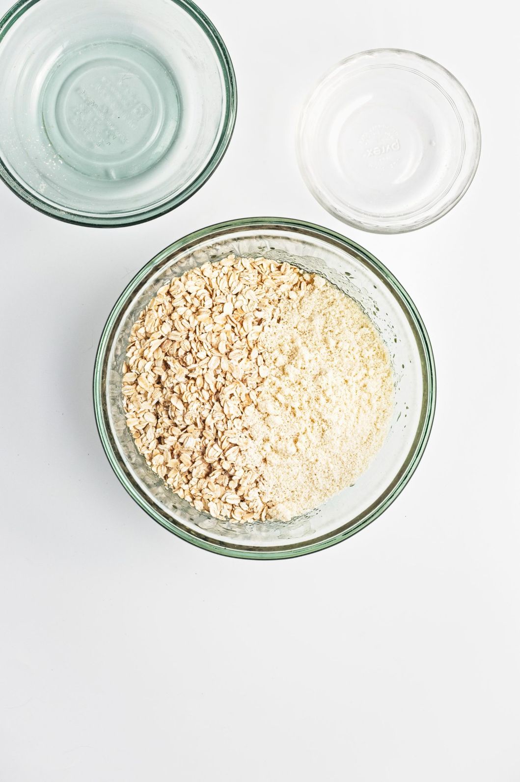 Rolled oats and almond flour added together in a glass bowl.