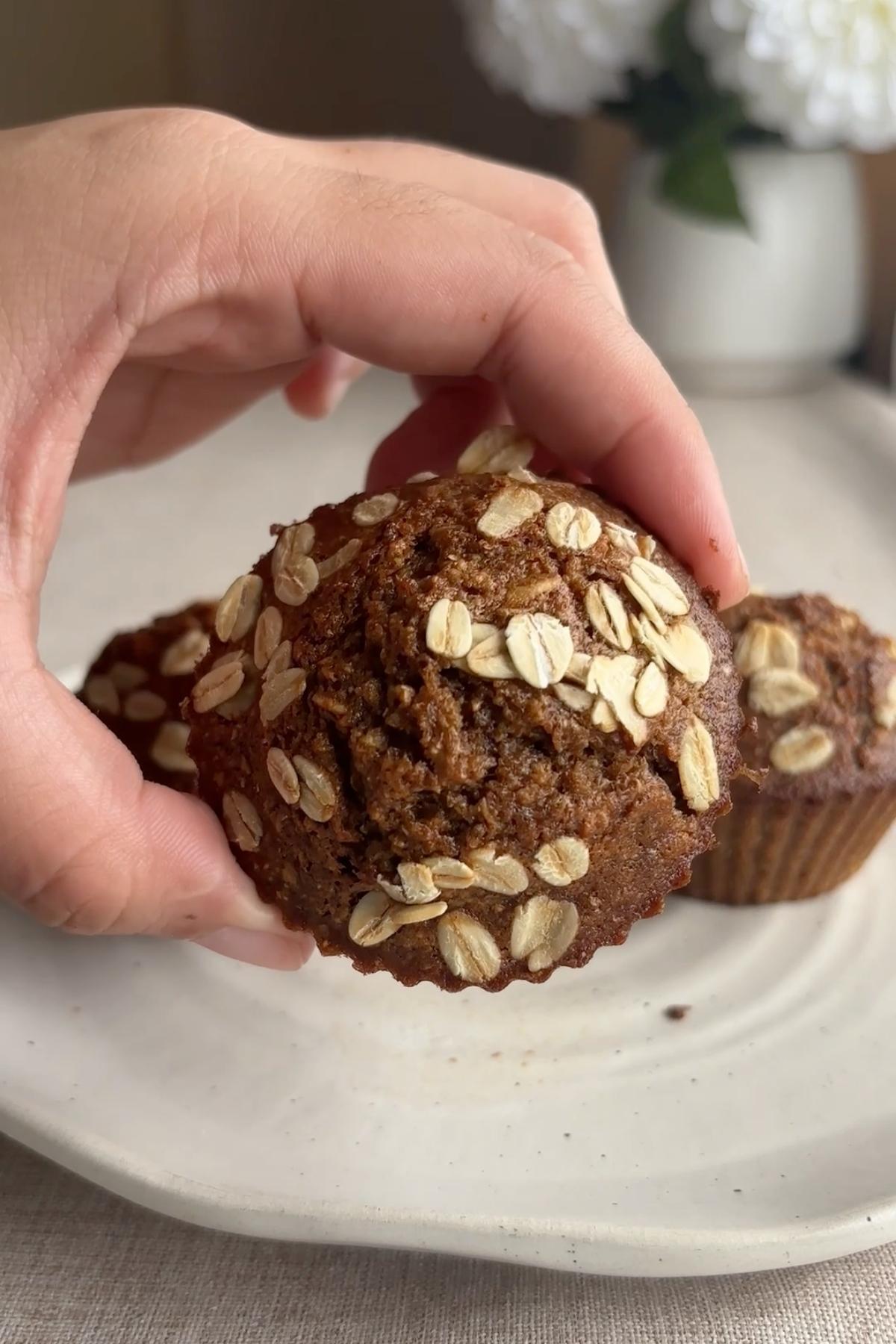 Hand holding muffin topped with oats.