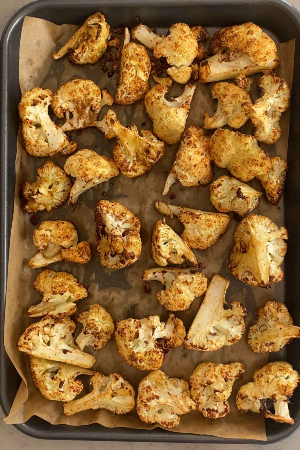 Golden roasted cauliflower spread across a lined baking tray.
