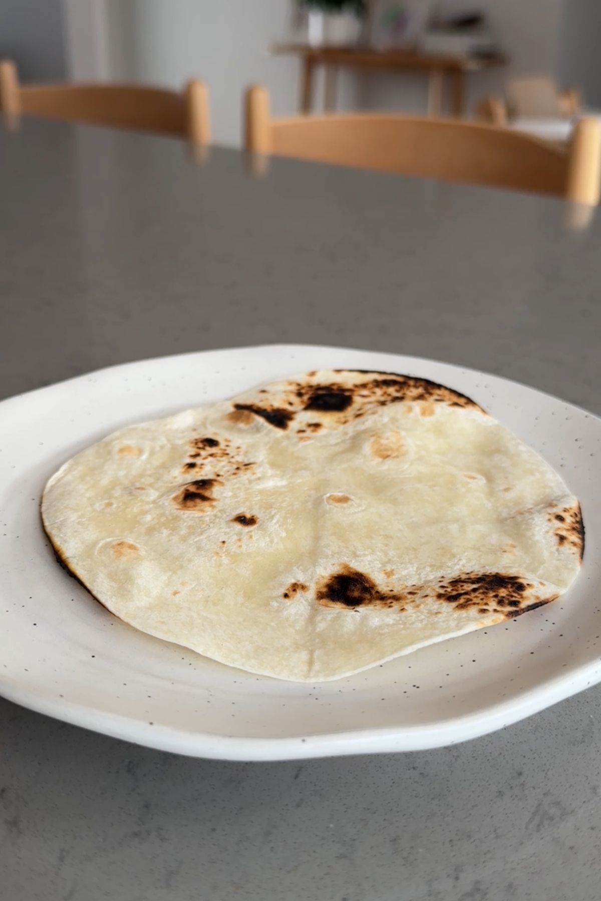 Lightly charred tortilla resting on a white ceramic plate.