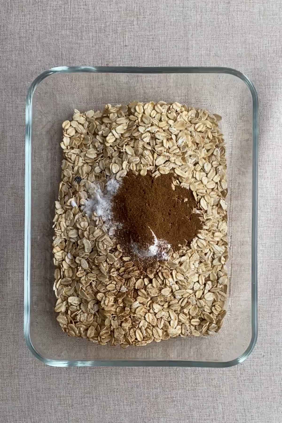 Rolled oats with spices and baking ingredients in a glass dish.