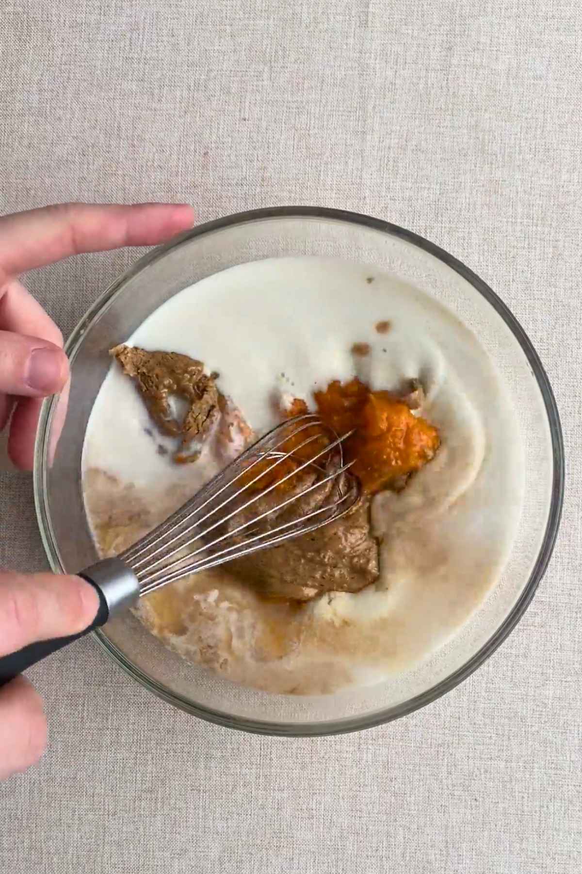 Pumpkin oat batter being mixed with a spatula in a glass baking dish.