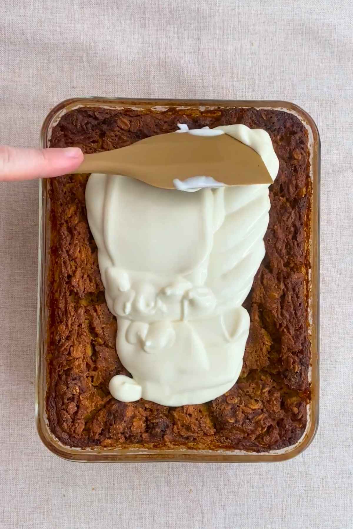 Yogurt being spread over baked oats with a spatula.