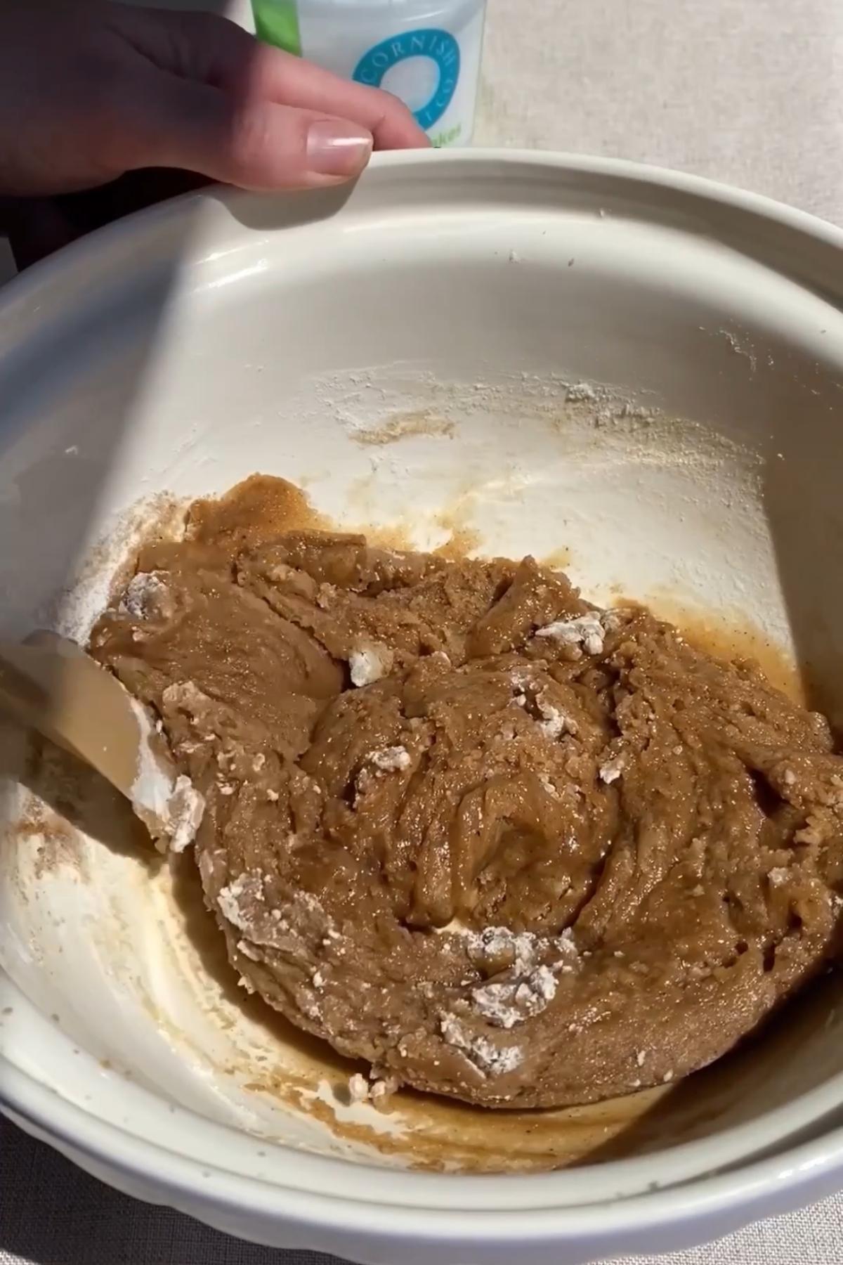 Brown sugar and melted butter with ground spices sitting in a mixing bowl before stirring.