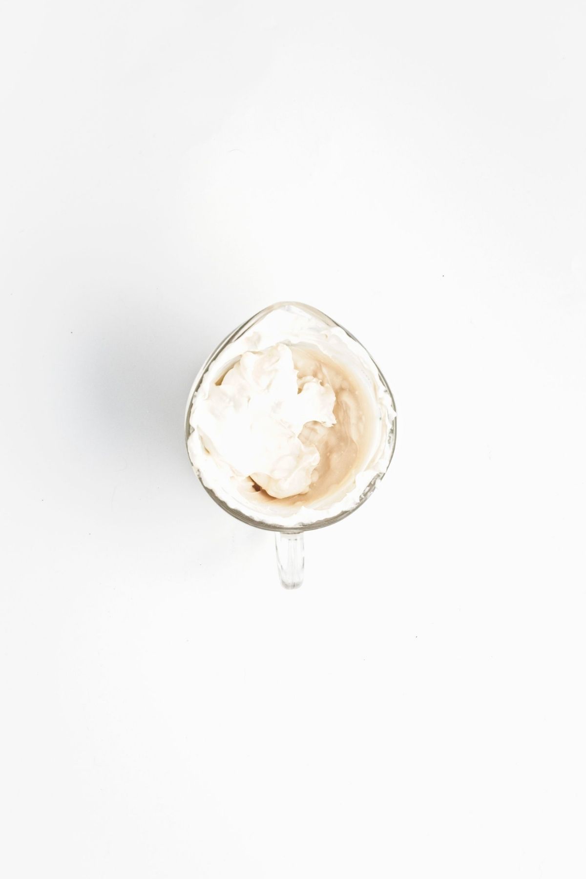 Thick white cream mixture in a small glass measuring cup.