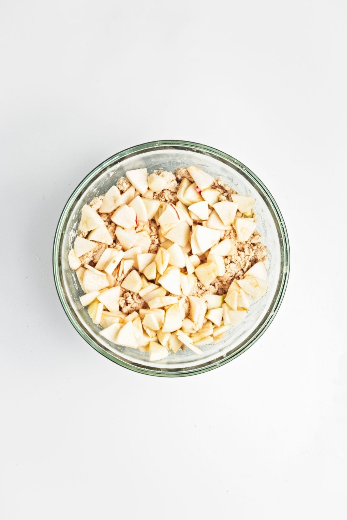 Bowl of dough mixed with small apple pieces.