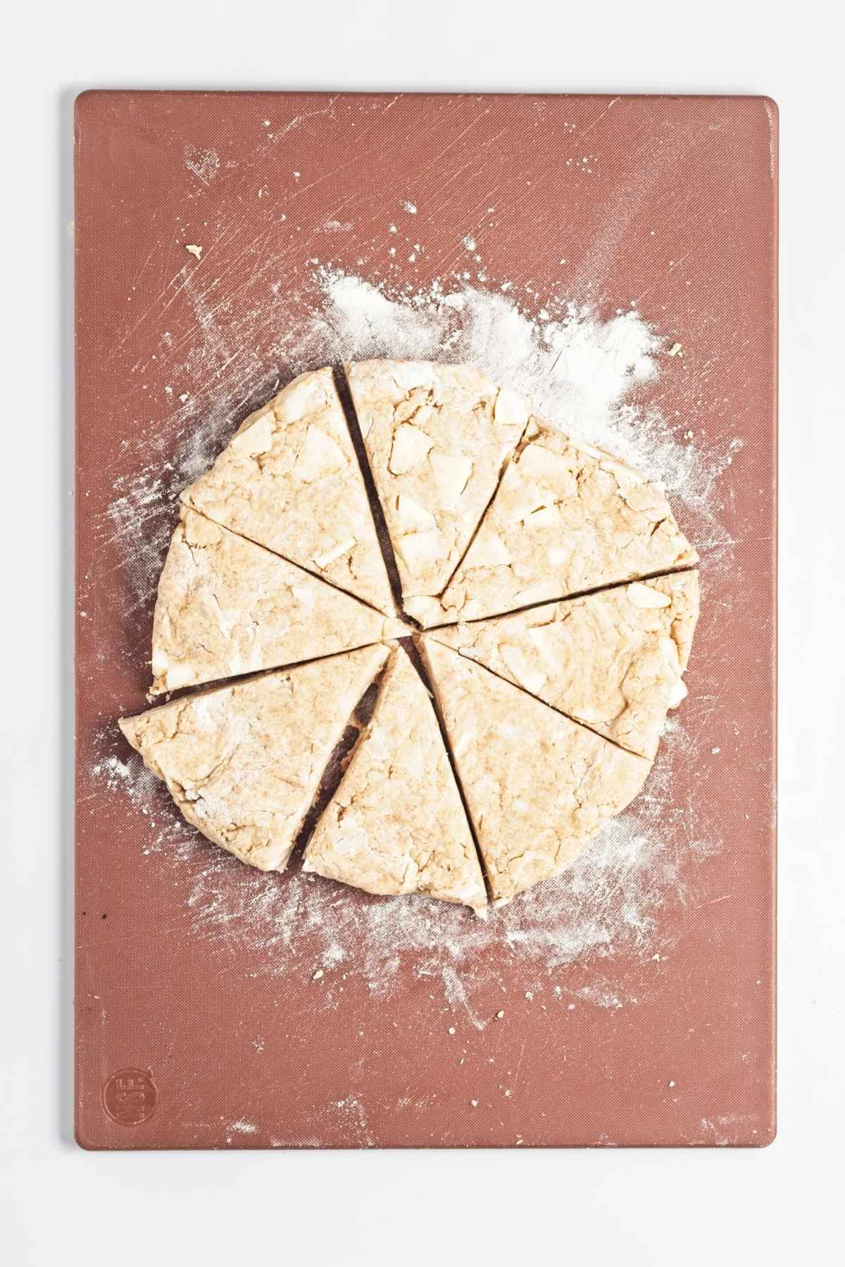 Round dough cut into eight triangle wedges on a floured board.